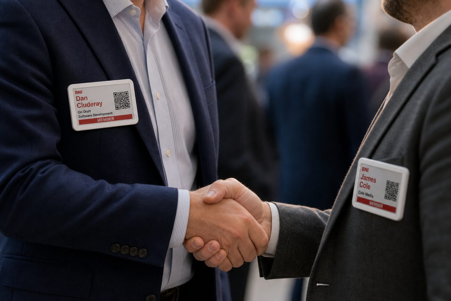 Dan Cluderay and James Cole shaking hands, white e-ink member badges on their lapels