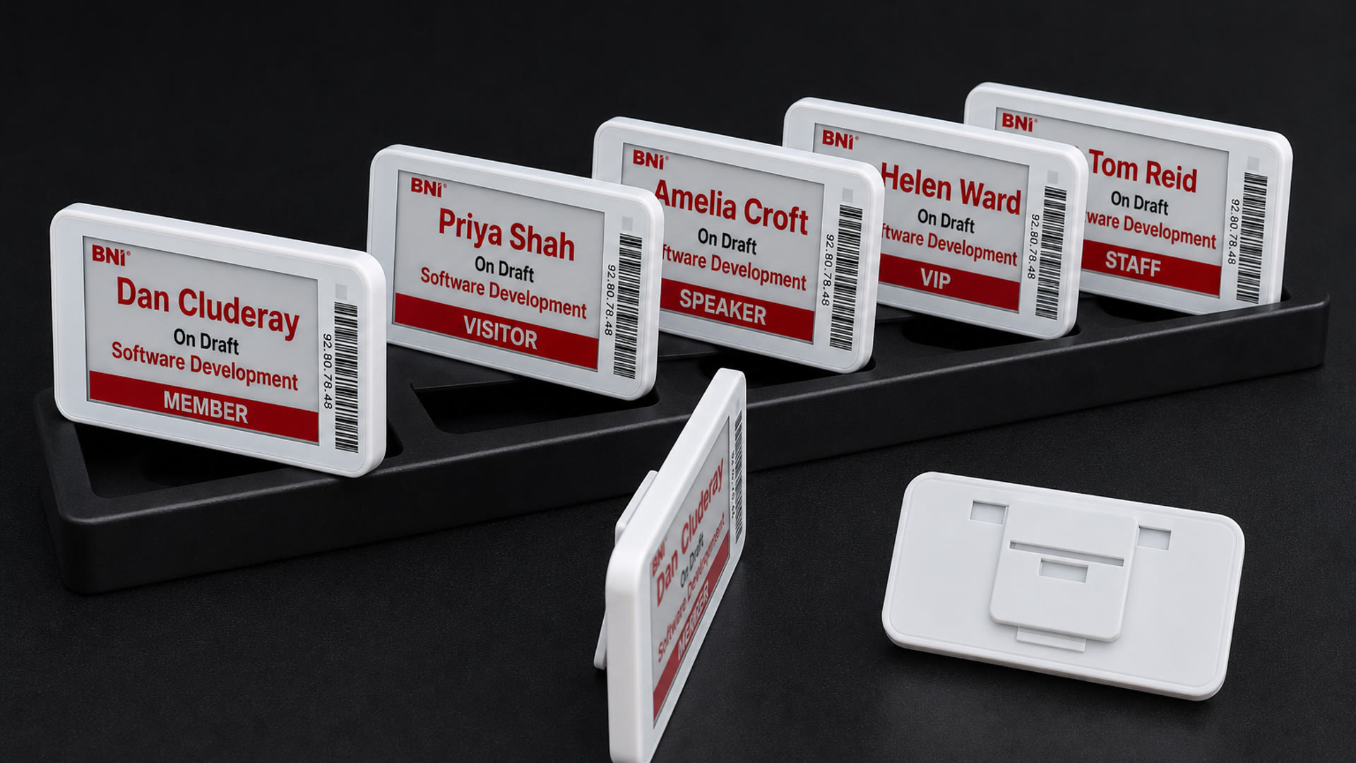 Kit tray of white-bezel e-ink badges showing member, visitor, speaker, VIP and staff faces